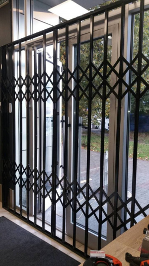 Раздвижная металическая решетка на двери окна витрины
